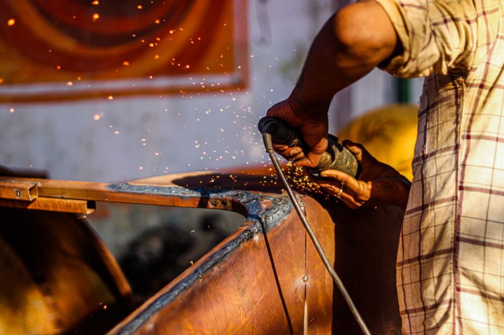Close-up of a craftsman using an angle grinder, emitting sparks in a metal workshop.