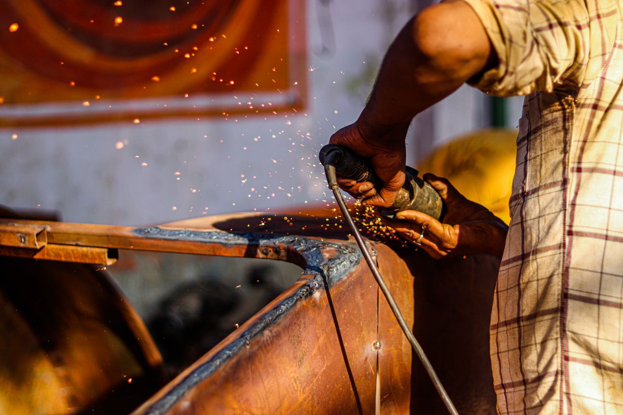 Close-up of a craftsman using an angle grinder, emitting sparks in a metal workshop.